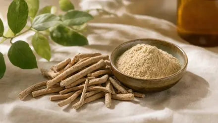 Getrocknete Ashwagandha-Wurzel (Withania somnifera) und Pulver in einer Holzschale auf hellem Leinen.